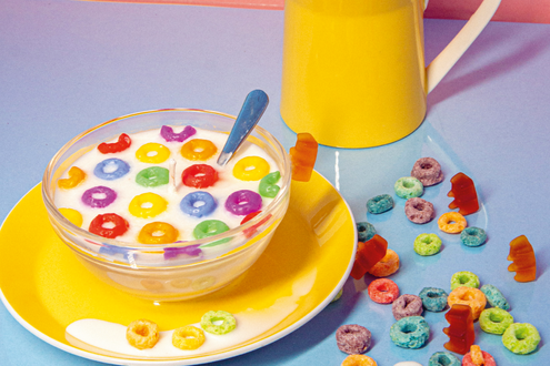 bunte Cerealien verteilt auf dem Tisch mit einem Krug Milch im Hintergrund
