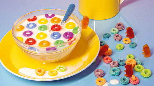 bunte Cerealien verteilt auf dem Tisch mit einem Krug Milch im Hintergrund