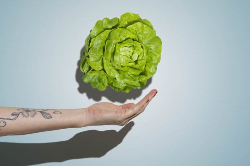 Hand wirft vorsichtig Salat