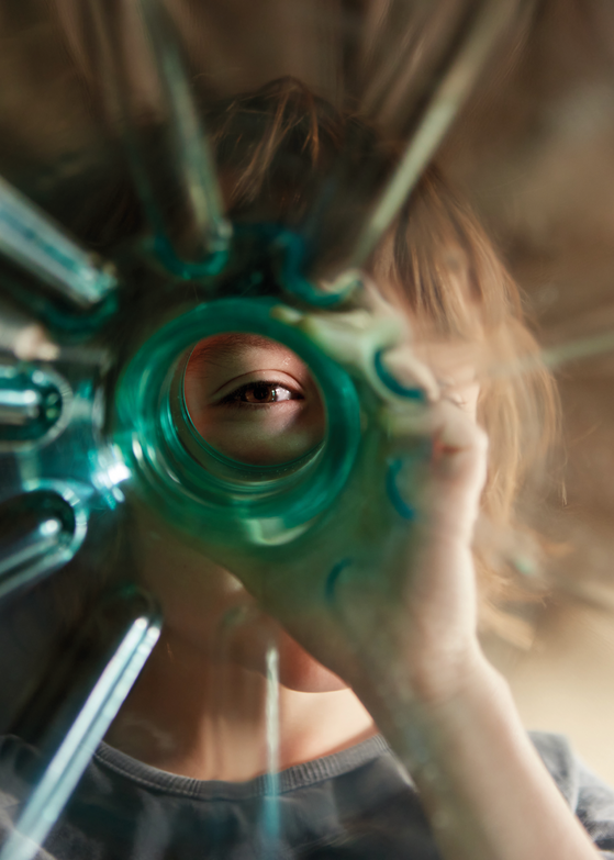 Person looking through the opening of a plastic bottle